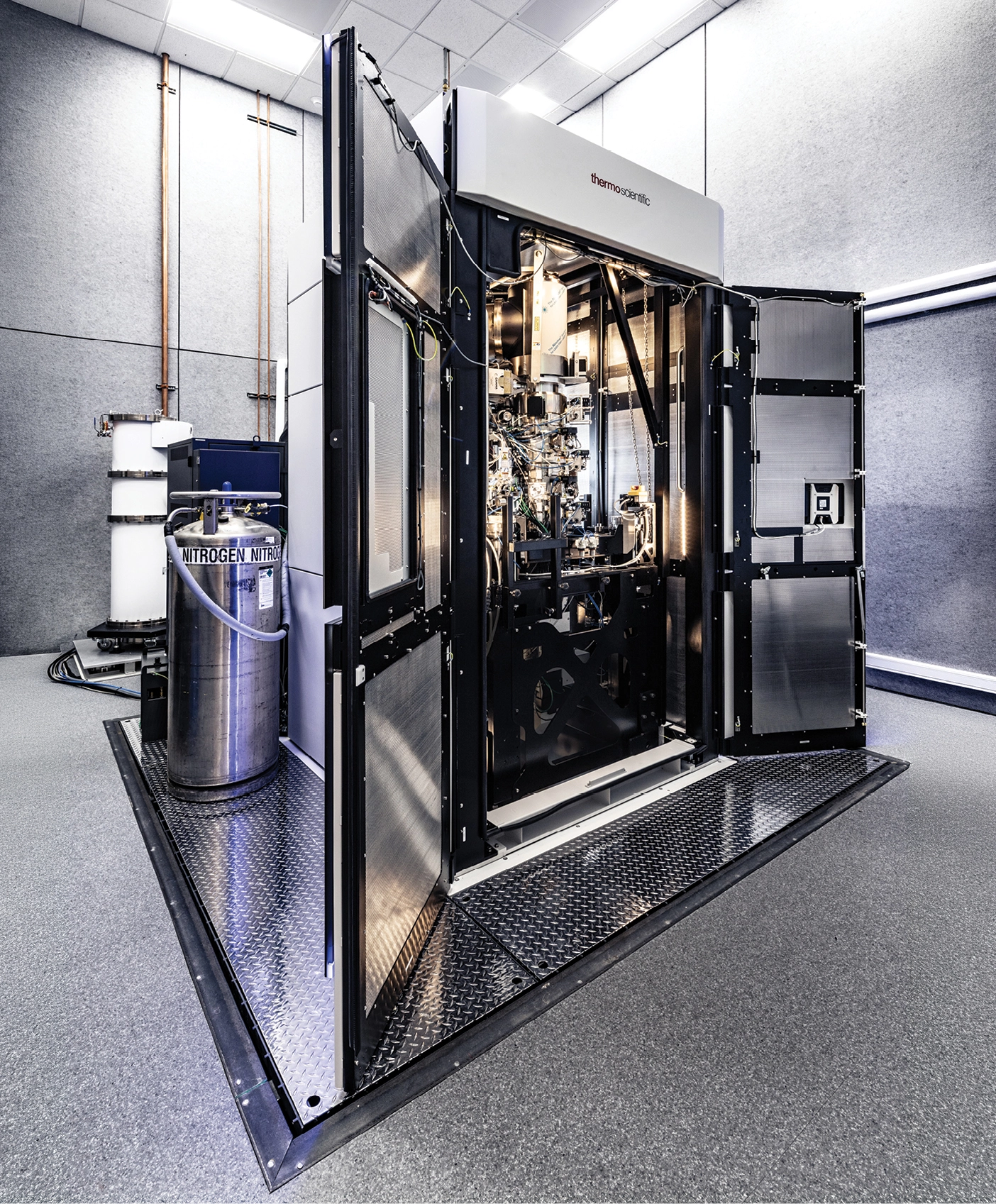 A large transmission electron microscope covered in wires sits inside a giant container that looks like an open fridge.