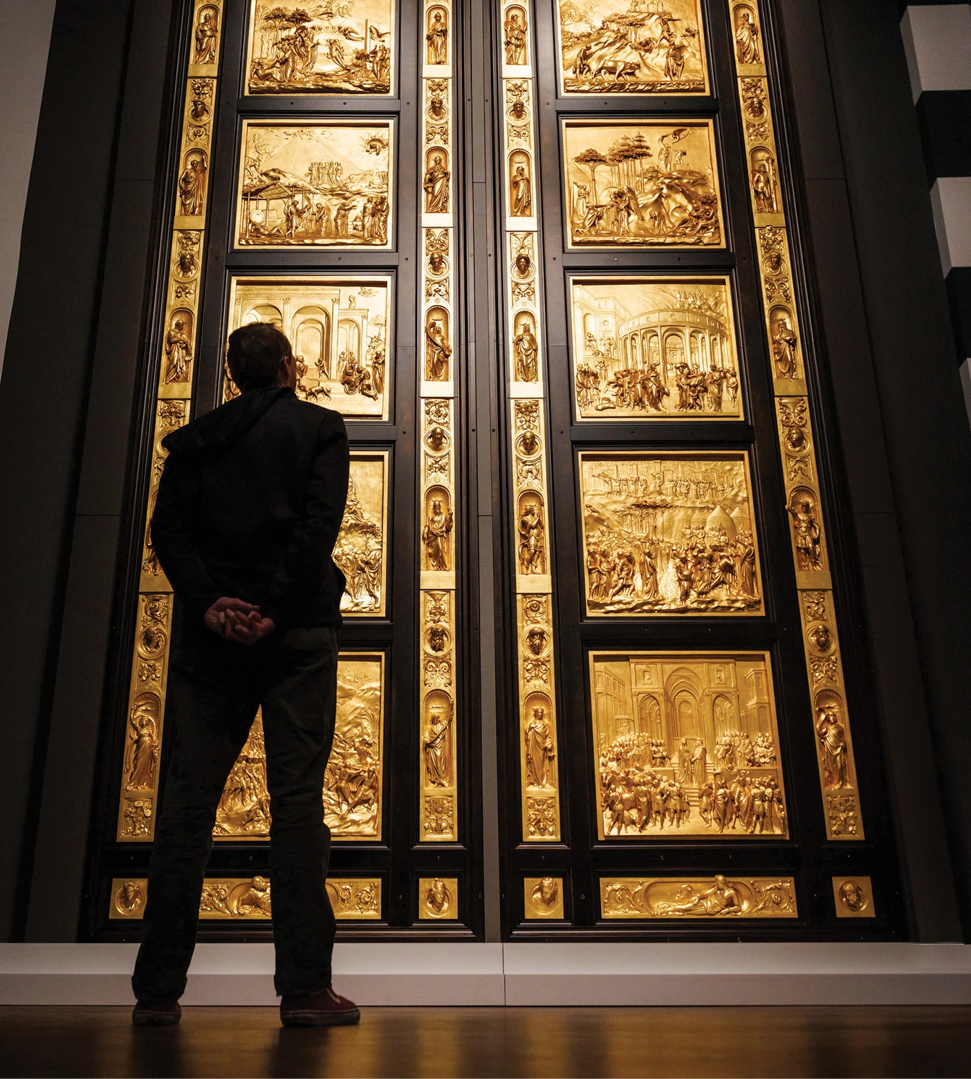 A person stands in front of a replica of the Gates of Paradise at BYU's Museum of Art.