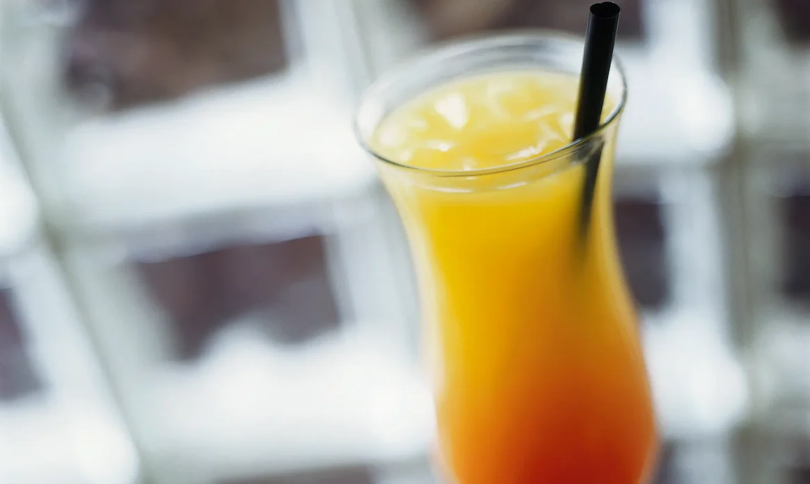 Tall glass of the Skyroom’s High in the Sky specialty drink, layered from deep red at the bottom to orange and yellow at the top, with a black straw.