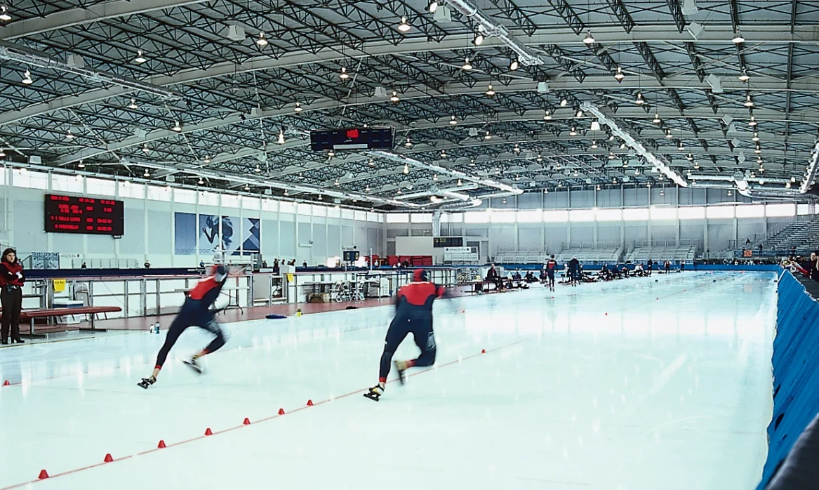 Two ice skaters race down the olympic track for the winter games in Utah.
