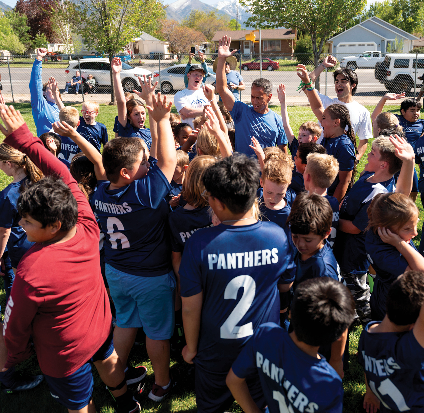 Children and coaches raise their hands in a cheer.