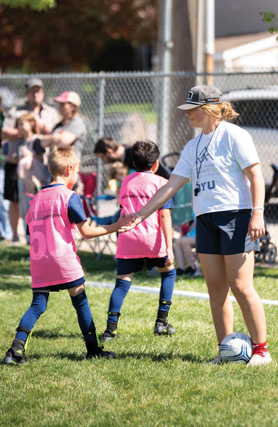 Children high-five their coach, a BYU student, during a soccer game.