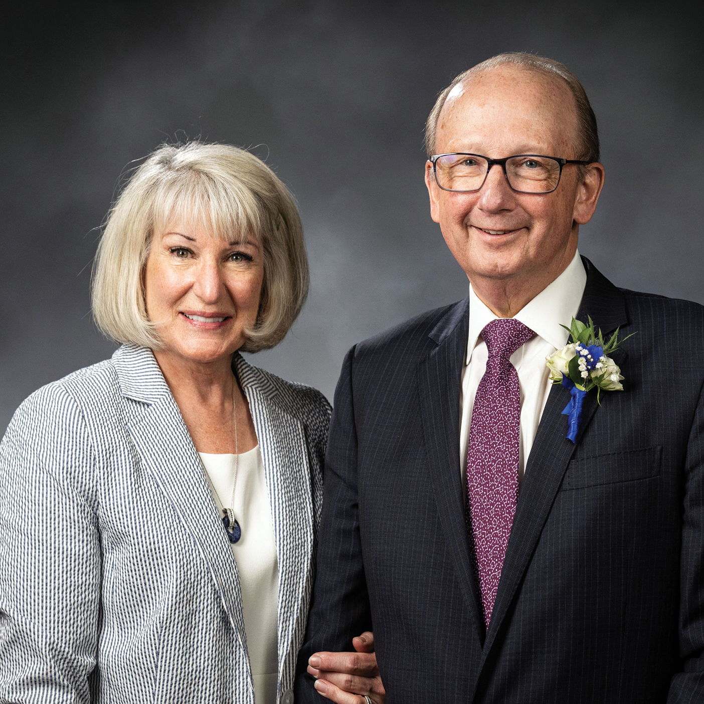 Rachel and David Weidman stand close together and smile for a portrait.