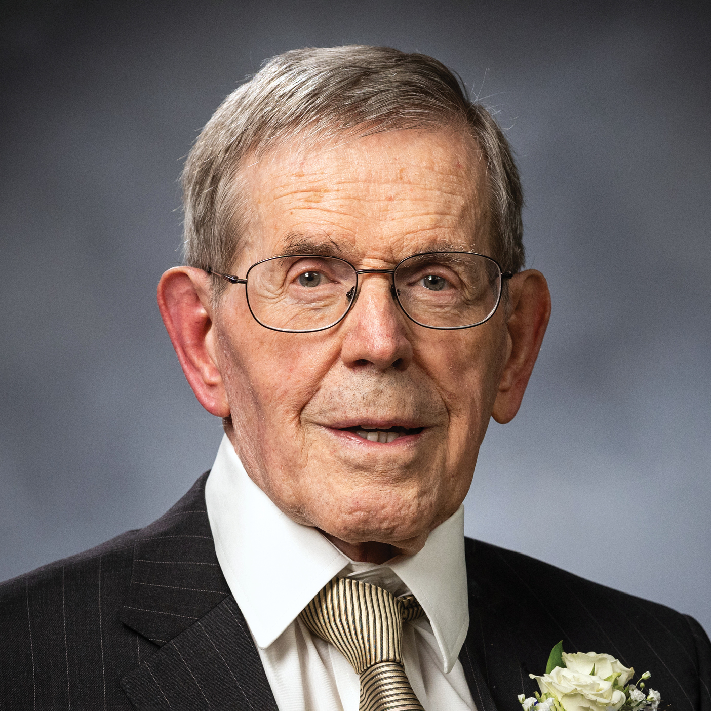 Bruce Hafen poses for a portrait against a gray background.