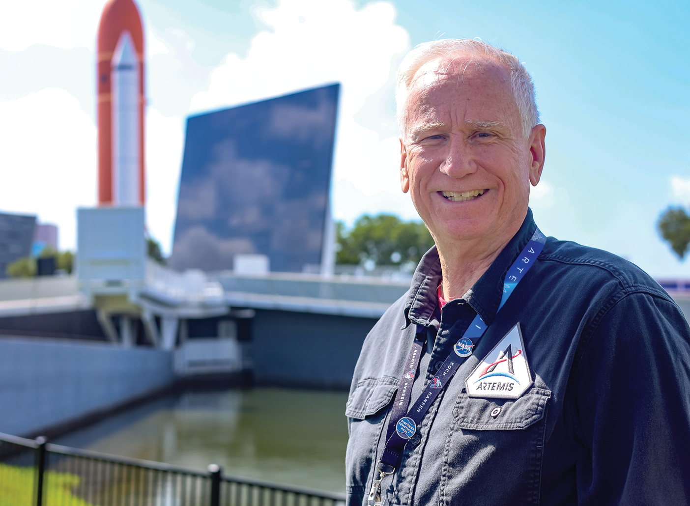 A photo of Steve Portz standing and smiling outside, with a rocket in the background.