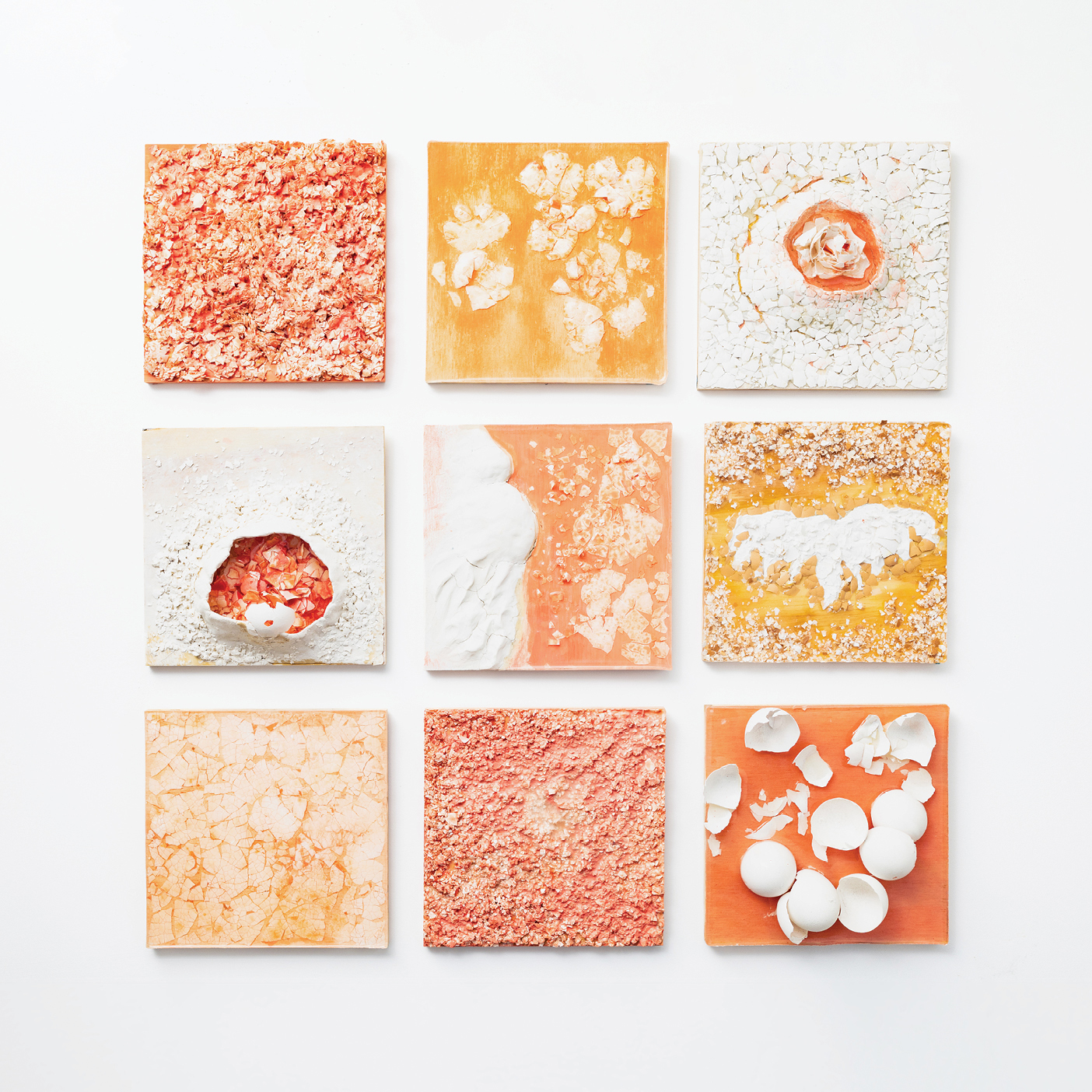 A 3-by-3 grid of nine square mixed-media panels in shades of orange, pink, and white, featuring abstract patterns and imagery of flowers, wings, wombs, and eggshells.